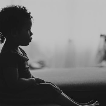 A simple silhouette of a person sitting peacefully against a soft background.